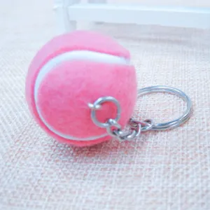 Primer plano de un lindo llavero de pelota de tenis rosa sobre un fondo.