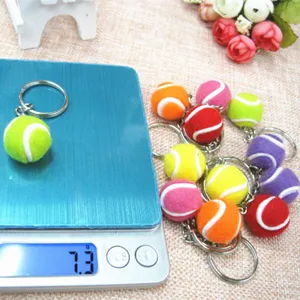 Precisieweegschaal toont het gewicht van 7,3 g van een mini-tennisbal sleutelhanger van 2 cm
