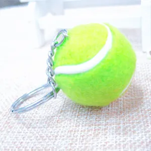Primer plano de un llavero de pelota de tenis de fieltro verde flúor con aro de metal.