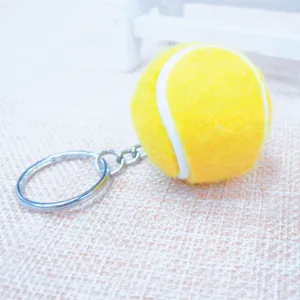 Primer plano de un mini llavero de pelota de tenis amarilla con un anillo plateado.