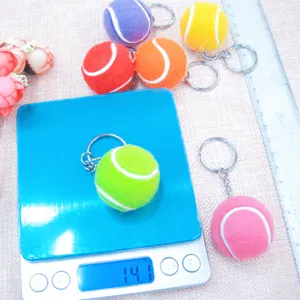 Primer plano de un colorido llavero de mini pelota de tenis en una báscula 14,1g