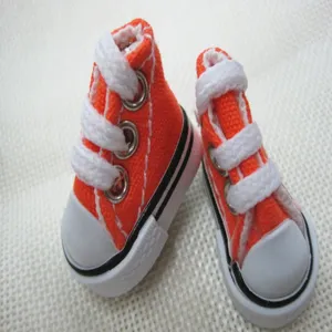 Macro view of tiny 3.5cm orange canvas sneakers for doll accessories or keychains.