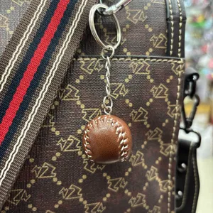 Detailed close-up of a brown faux-leather baseball keychain hanging on a designer style bag