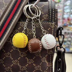 Detailed view of three baseball and softball keychains in yellow, brown, and white