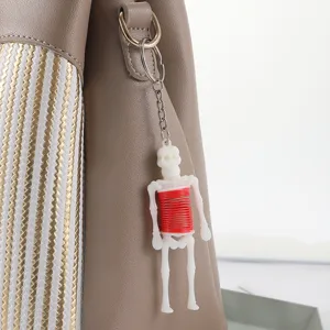 Nahaufnahme eines ausziehbaren Skelett-Schlüsselanhängers mit roter Feder am Beutel.