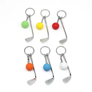 Detailweergave van zes kleurrijke golfbal- en club metalen sleutelhangers op wit