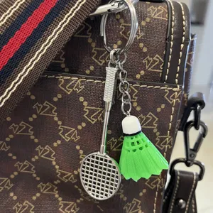 Detailopname van mini badmintonracket en groene shuttle-sleutelhanger aan een bruine tas