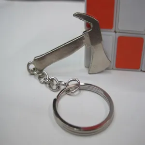 Macro detail of a silver miniature metal axe pendant on a stainless steel key ring.