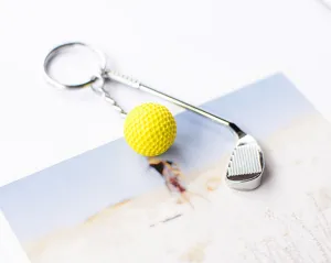 Close-up van een zilveren metalen golfclub en gele golfbal sleutelhanger hanger