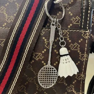 Close-up van een creatieve badmintonracket en shuttle-sleutelhanger op een bruine handtas