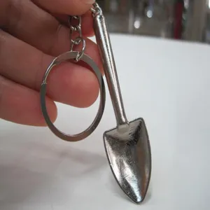 Close-up detail view of a mini metal shovel keychain with silver finish and ring