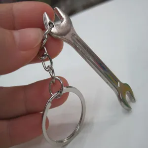 Detailed close-up view of a mini silver metal wrench keychain accessory held by hand.