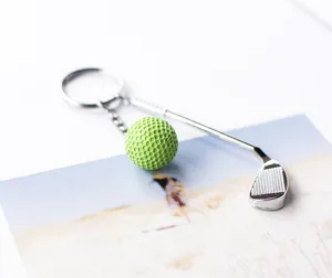 Detailopname van een creatieve metalen golfclub en groene golfbal bedeltje aan een sleutelhanger
