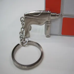 Close-up detail of a silver miniature electric drill tool keychain with metal ring