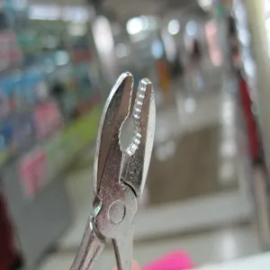 Macro detail of miniature stainless steel pliers keychain head with textured grip