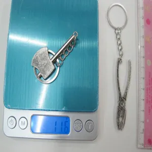 Detail view of mini metal tool keychains with weight on scale and size reference ruler.