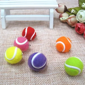 Nahaufnahme von bunten Mini-Tennisball-Anhängern auf strukturiertem Grund.