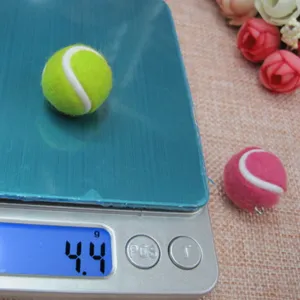 Nahaufnahme eines 2 cm großen Mini-Tennisball-Anhängers auf einer Digitalwaage mit 4,4 g