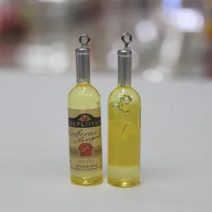 Détail de breloques miniatures en forme de bouteilles de vin en résine réalistes