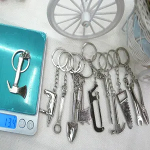 Detailed close-up of various miniature metal tool keychains set showing weight on scale