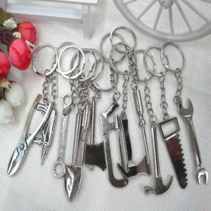 Close-up of various mini metal tool keychains like shovel, saw, hammer and wrench.