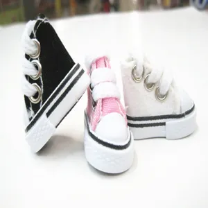 Close-up detail of three mini 3.5cm canvas doll shoes available in black, pink and white