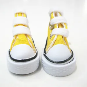 Macro detail of 3.5cm mini yellow canvas sneakers for dolls and keychains with white soles.