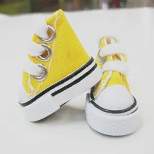 Close-up of 3.5cm mini yellow canvas doll sneakers with white laces and rubber soles.
