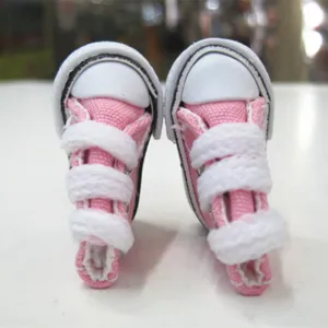 Close-up detail of 3.5cm mini pink canvas doll shoes with white laces for accessories