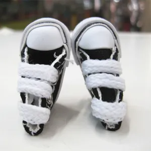 Close-up macro detail of 3.5cm miniature black canvas shoes for dolls and keychains