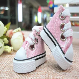 Detailed macro view of two miniature pink canvas high-top sneakers for doll accessories.