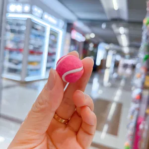 Detaillierte Nahaufnahme eines lebhaften rosa Mini-Tennisball-Schlüsselanhängers in Hand.