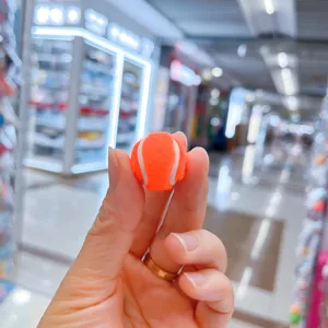 Nahaufnahme eines winzigen orangefarbenen Tennisball-Anhängers, der die kleine Größe zeigt.