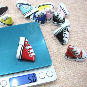 Detailed view of a miniature 3.5cm colorful canvas shoe being weighed on a digital scale.