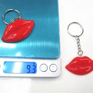 Detail view of a red resin lip keychain being weighed at 9.3g on a digital scale