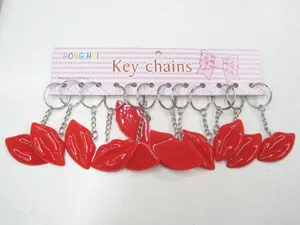 Set of glossy red resin lip keychains presented on a pink display packaging strip