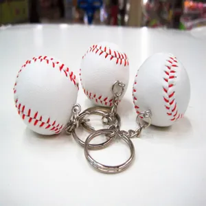 Detailopname van witte honkbal sleutelhangers met rode stiksels en zilveren ringen.