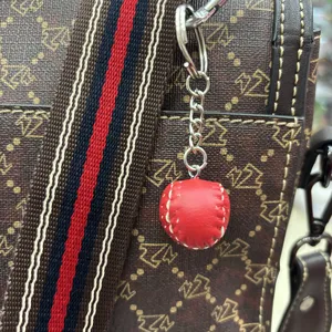 Mini red leather baseball keychain accessory with hand-stitched detail on bag strap