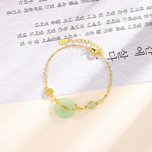 Détail de bracelet en chaîne dorée avec jade vert Ping'an Kou et breloque Fu