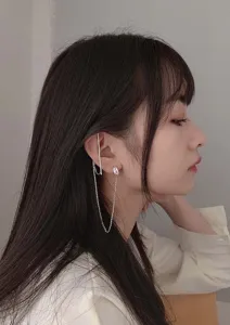 Elegante zilverkleurige oorklem met lange ketting en zirkoon gedragen door model.