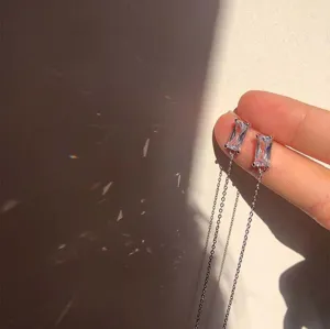 Detailweergave van minimalistische punk oorbellen met zilveren ketting en zirkonia studs.
