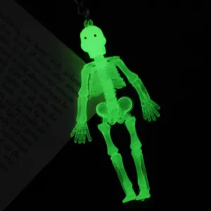 Primer plano de un llavero de esqueleto de Halloween verde brillante en la oscuridad