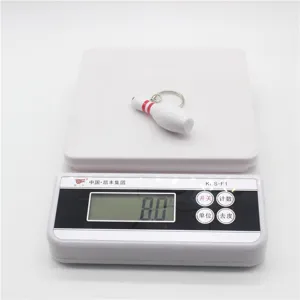 Detailweergave van een witte bowling kegel sleutelhanger die 8,0 gram weegt op een schaal