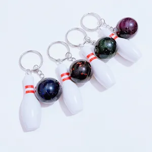 Detail showing four mini bowling pin keychains with colorful glitter balls.