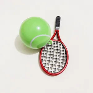 Detailed close-up of a miniature red tennis racket and bright green ball accessory.
