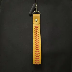 Detailed shot of yellow leather baseball keychain with vibrant red cross-stitching