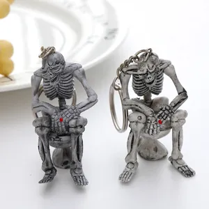 Close-up of skeleton sitting on toilet keychains in two different colors for Halloween decor