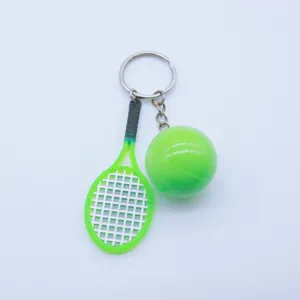 Close-up detail of a miniature neon green tennis racket and ball keychain accessory