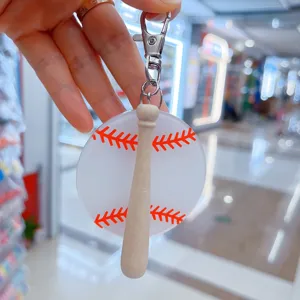 Detail view of a clear acrylic baseball keychain pendant with a mini wooden bat charm.