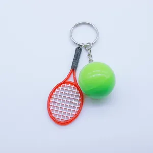 Close-up detail of a creative mini red tennis racket and green ball keychain accessory.